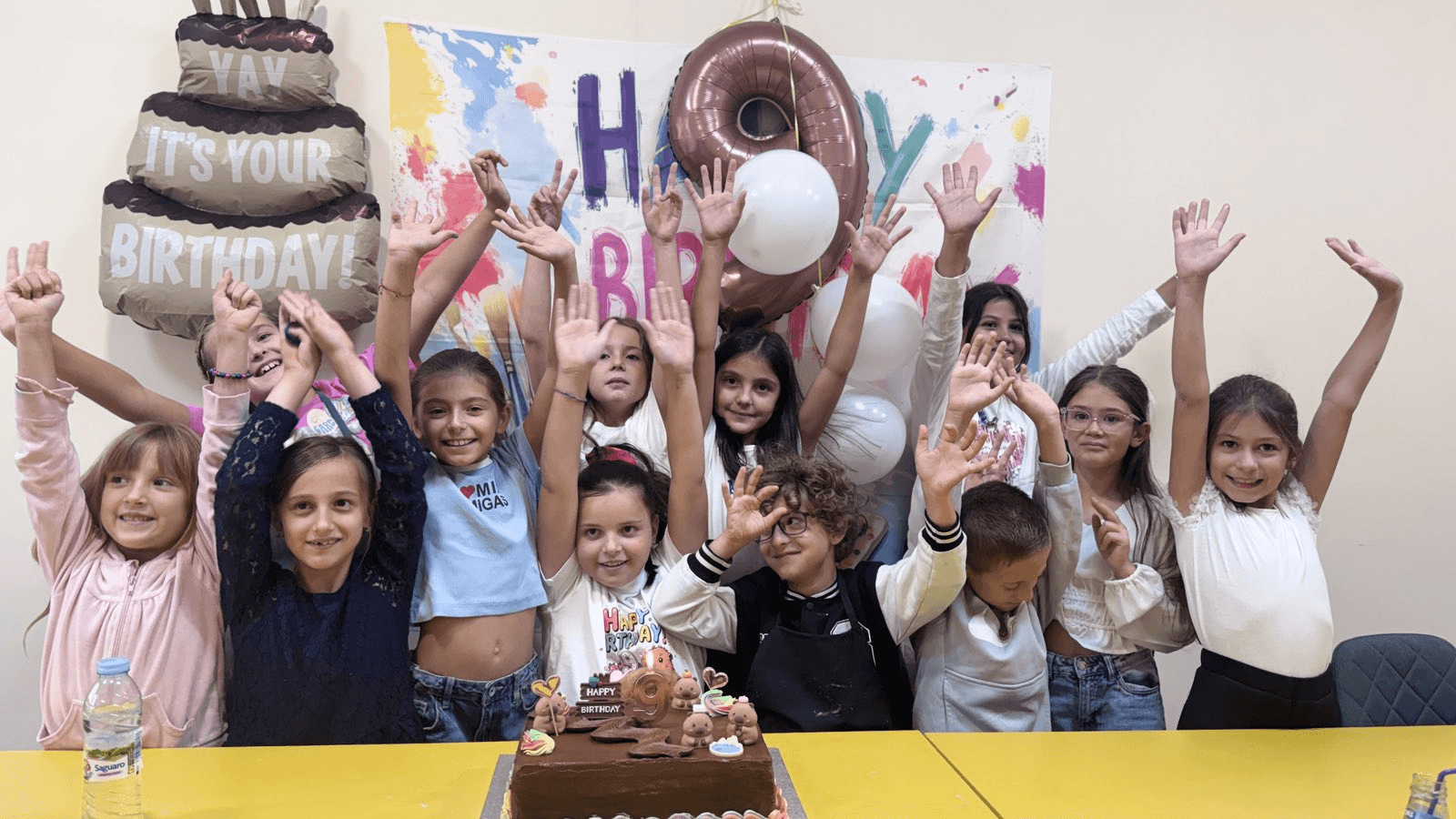 Деца празнуват 9-и рожден ден в ателието — торта, балони и банер Happy Birthday