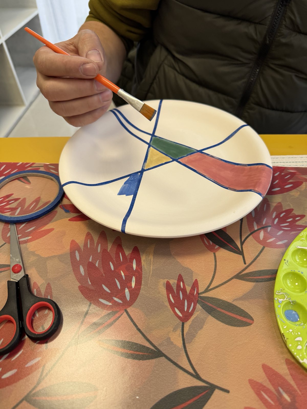 Гости рисуват заедно около маса в светлото ателие за керамика