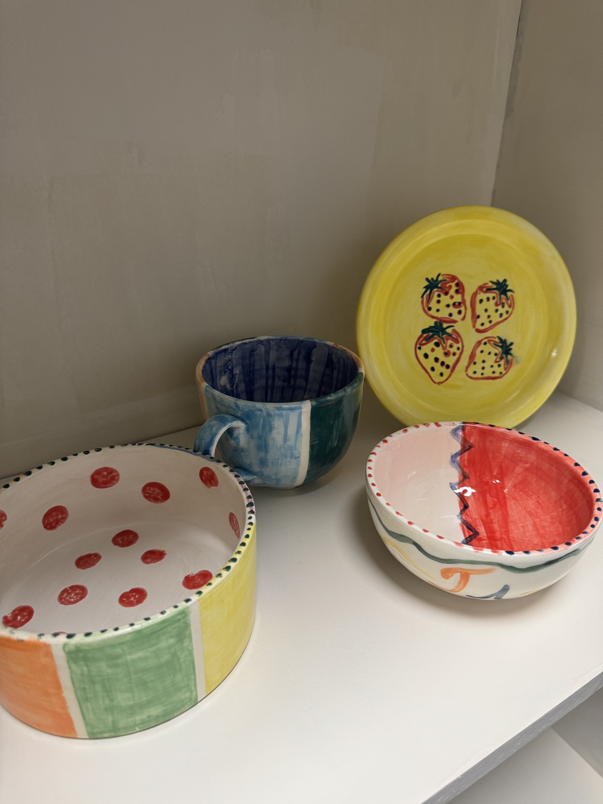 Ред изсушаващи се ръчно рисувани керамични изделия на рафт