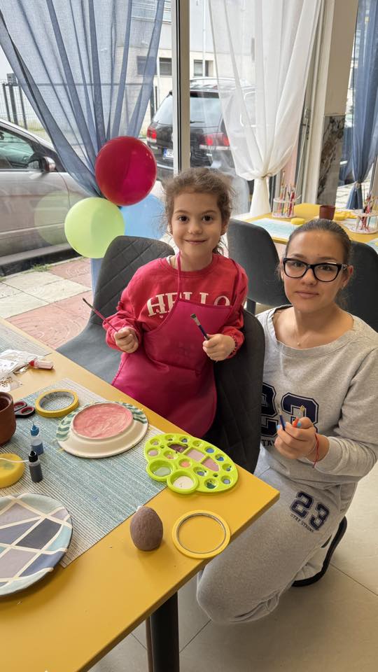 Участници в работилница показват готовите си изрисувани керамики